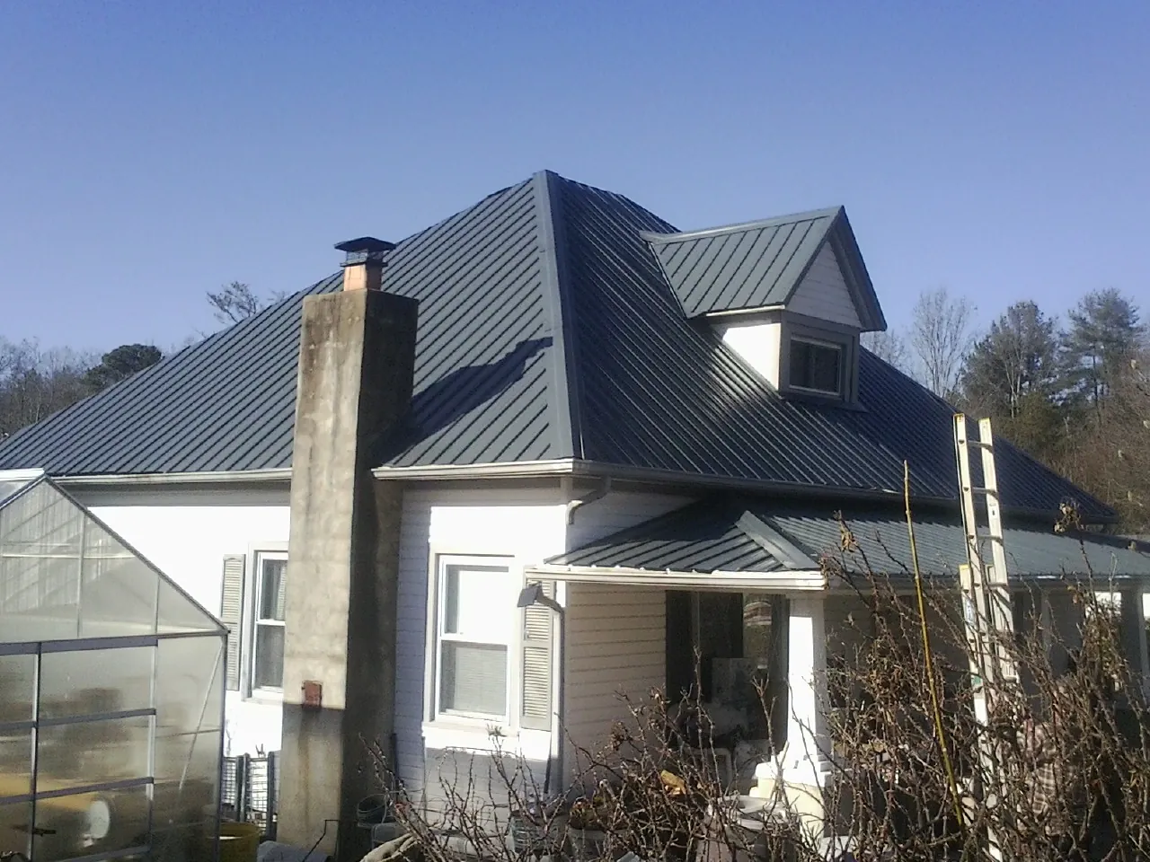 Dark blue standing seam metal roof on a white farmhouse with dormer — Slate & Tile Roof Repair by Roofing Brothers in Martindale