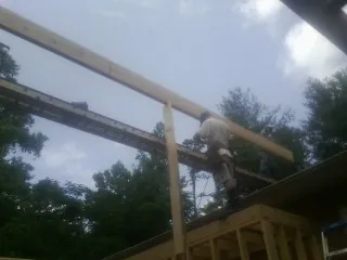 Carpenter setting a ridge beam over a new addition frame — Ice Dam Removal by Roofing Brothers in Martindale