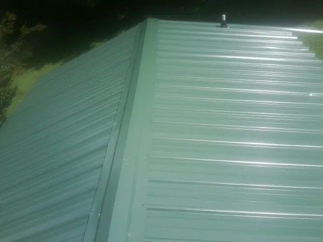 New green metal panels meeting at the ridge of a roof — Flat Roof Repair work by our crew in Martindale