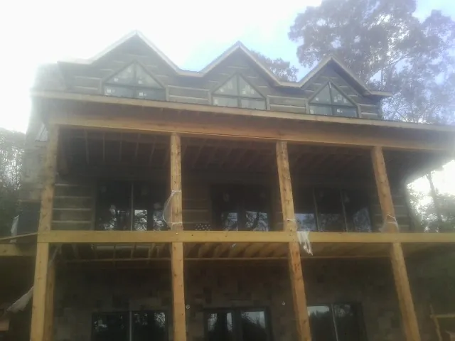 Dormers and porch framing on a large log home under construction — Roof Coating work by our crew in Martindale