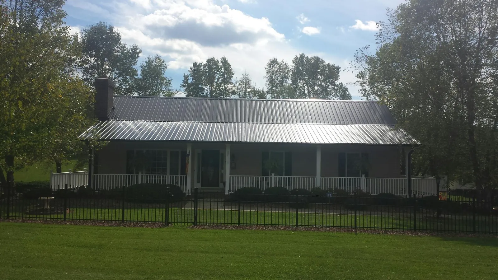 Gray metal roof on a brick ranch with a full width front porch — Gutter Guard Installation work by our crew in Martindale