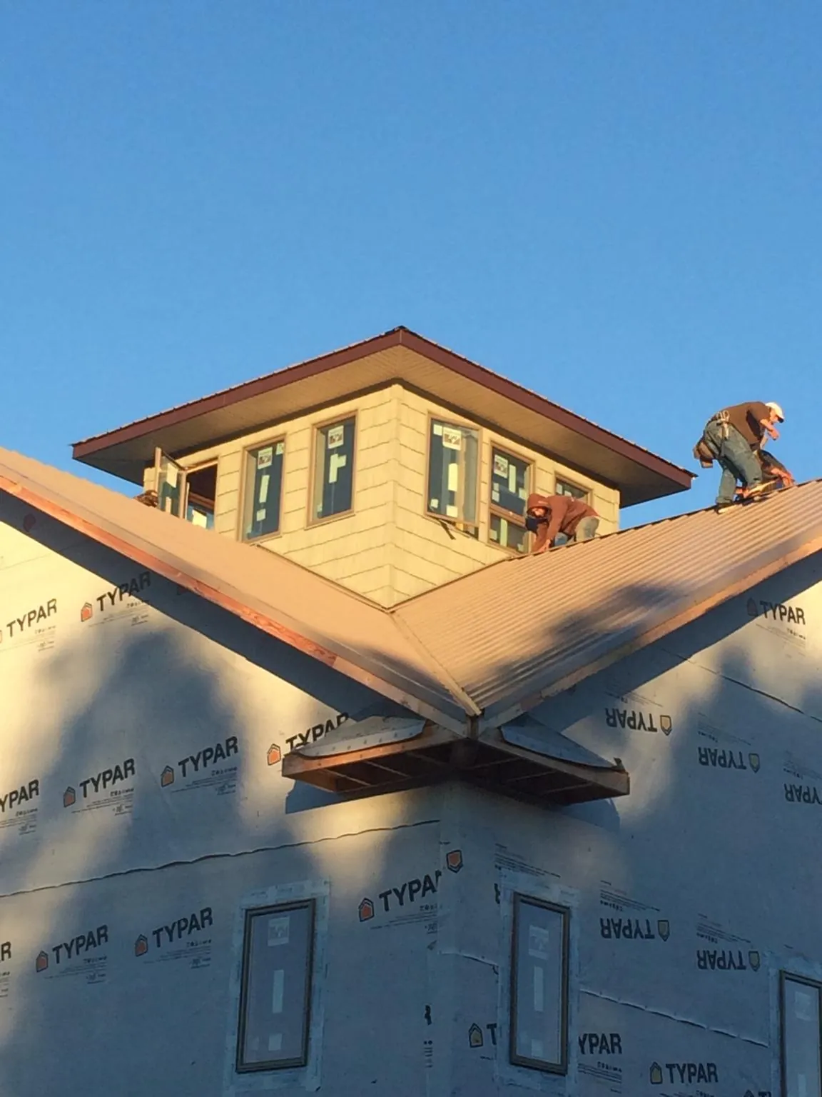 Roofers working around a rooftop cupola on a new metal roof at sunset — Roof Waterproofing in Martindale by Roofing Brothers